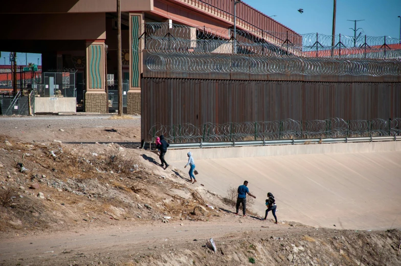 several people walking in the dirt near a wall