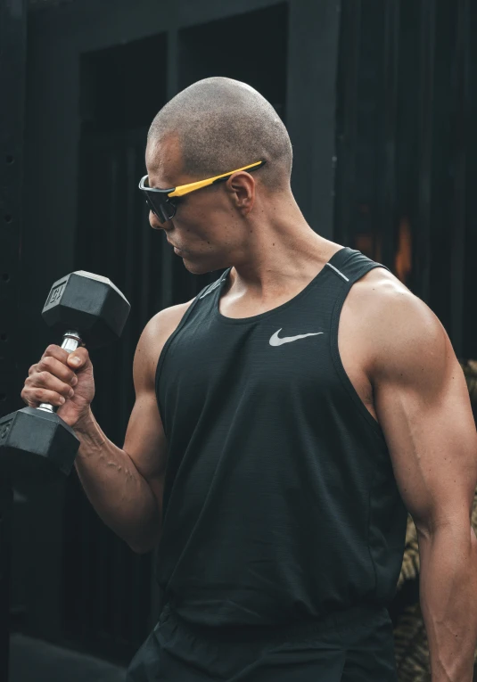 a man with sunglasses and a black shirt is holding two dumbbells