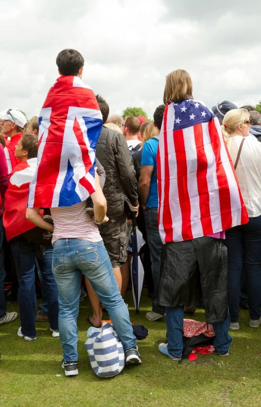 people holding flags stand on grass in the sun