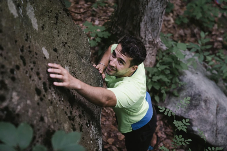 a man is climbing up a mountain while wearing green