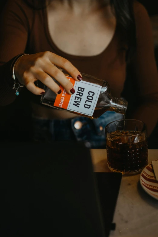 the woman is holding a bottle of alcohol next to a glass