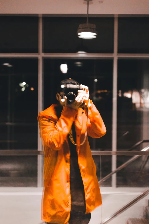 a man in an orange jacket taking a picture