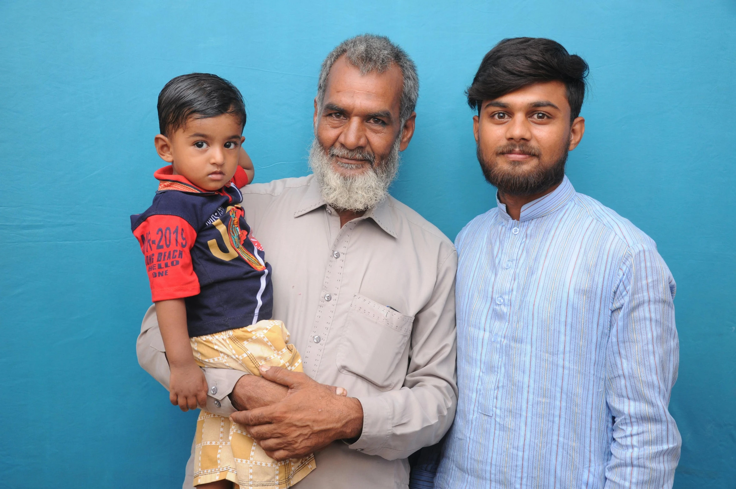 two men standing next to each other with a little boy on their shoulder