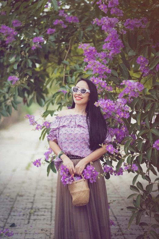 a woman with sunglasses is posing under a tree