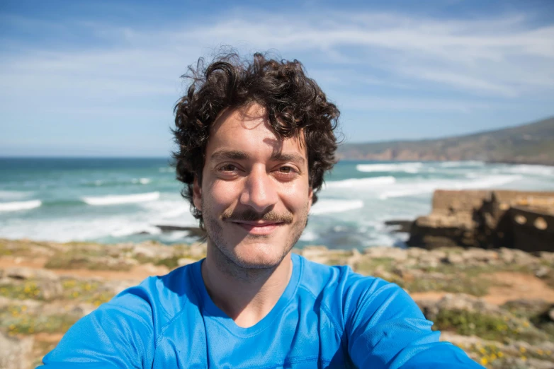 a man looking away while standing in front of the ocean