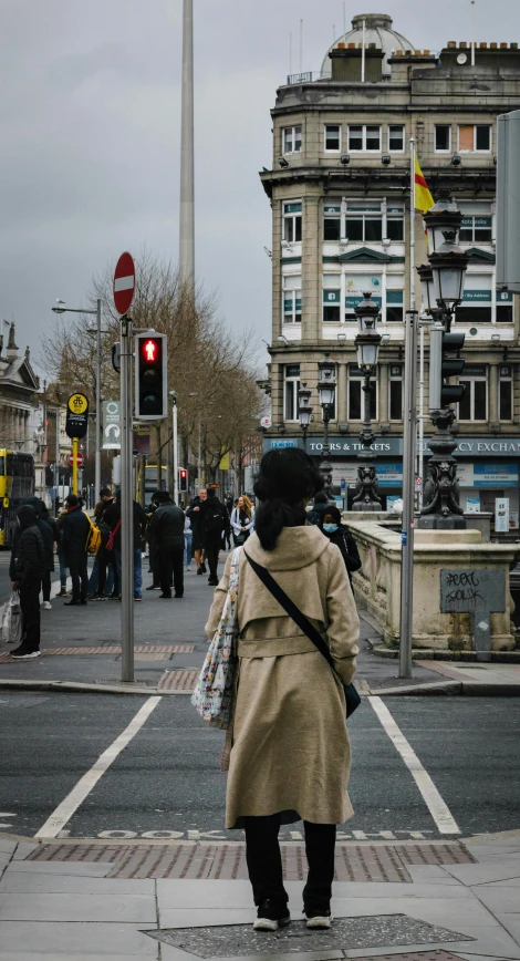 a woman stands on the corner next to a cross walk