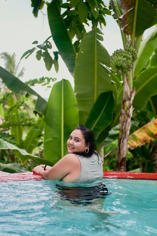 a young woman sitting in the pool smiling