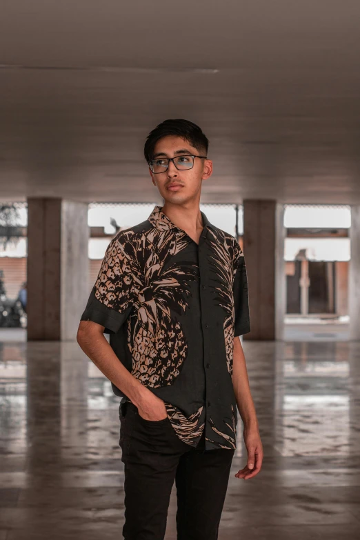 a young man wearing a hawaiian shirt and standing in an empty building