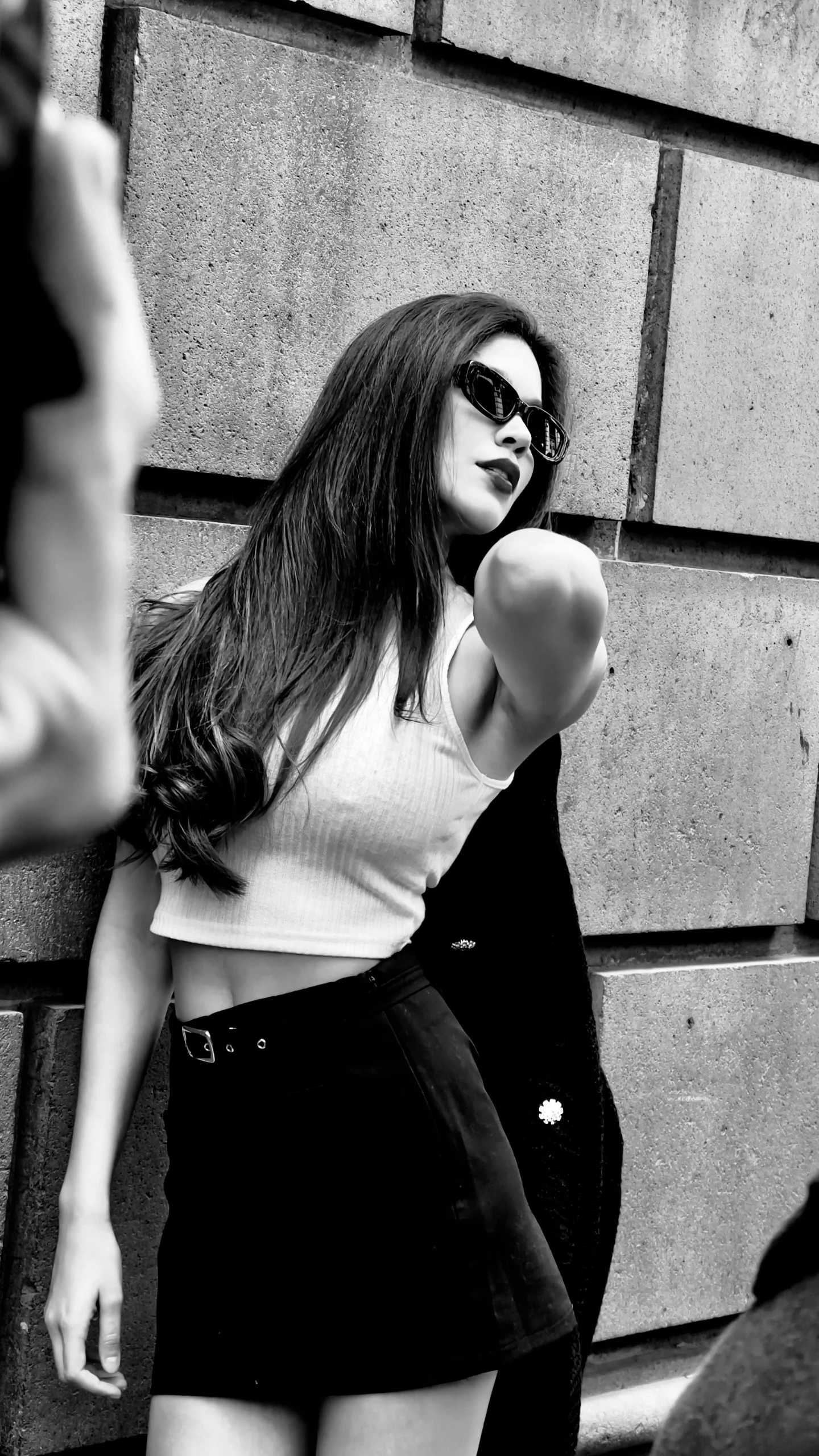 a woman is posing against a brick wall