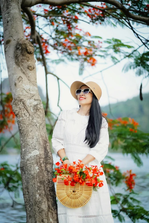 a young woman is standing next to a tree