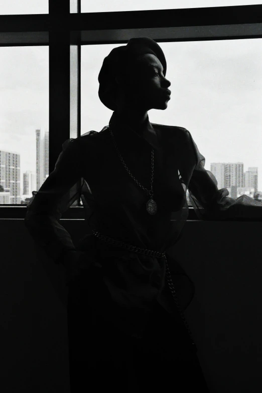 a black woman leaning against a window with her hand on her hips