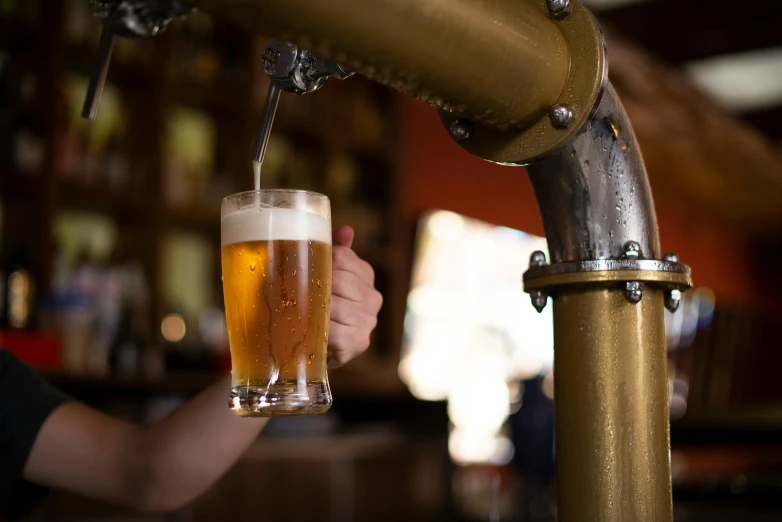 person pouring beer from keg into glass in bar