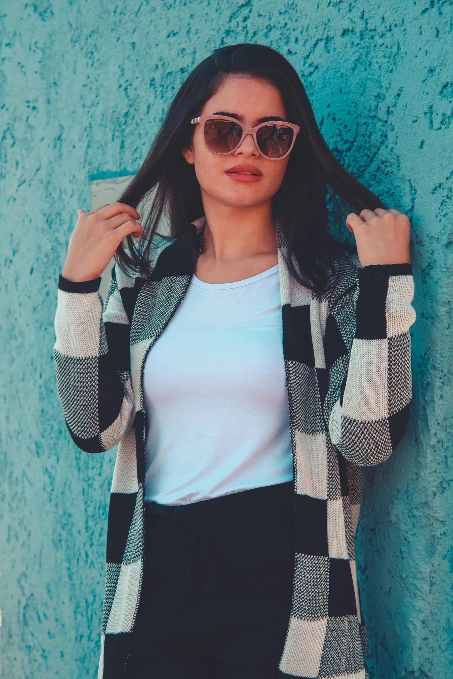 the woman is posing by the wall wearing a sweater and jeans