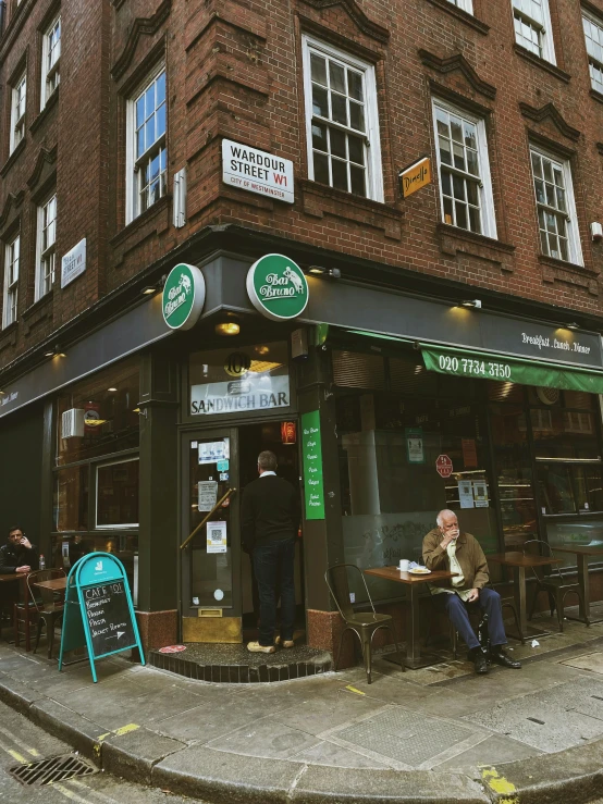 two people sitting outside of a store on the street