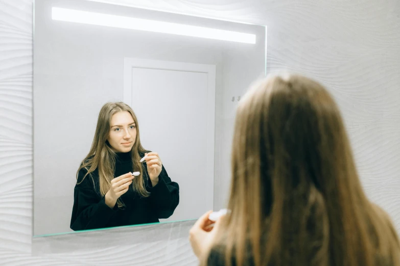 woman brushing her hair and looking at herself in the mirror
