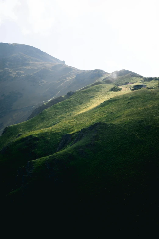 a green hill under a cloudy sky on the side of a hill