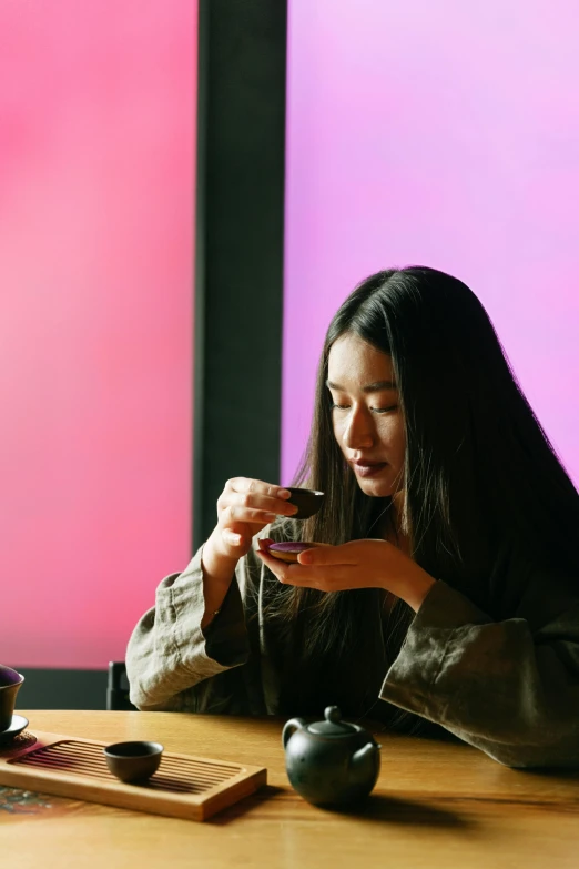 a woman sitting at a table with a cup and phone