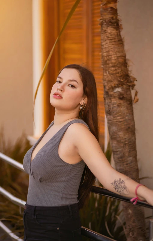 a woman standing by a tree leaning up against railing