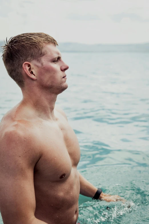 a shirtless man stands in the water