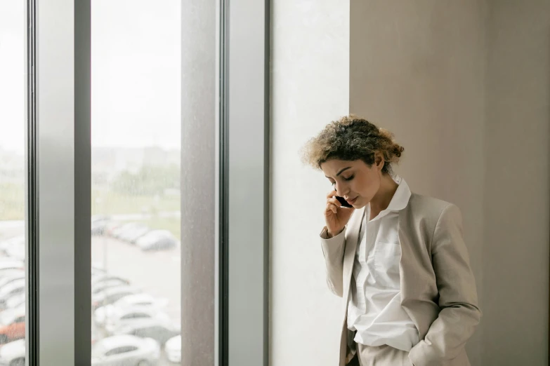 a young woman is on her cell phone looking out the window