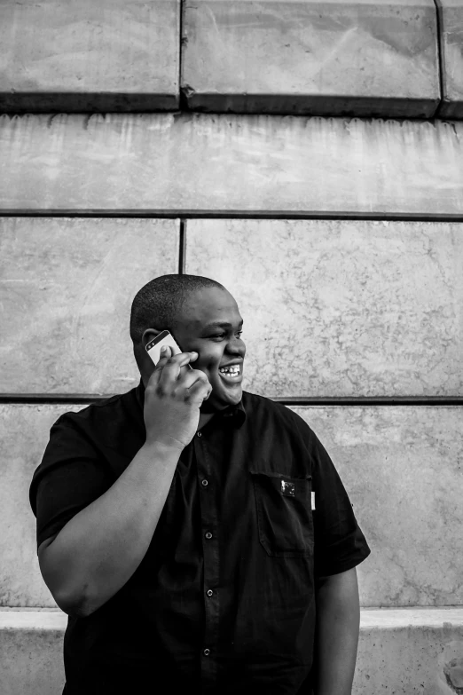 a man talking on his cell phone next to a wall