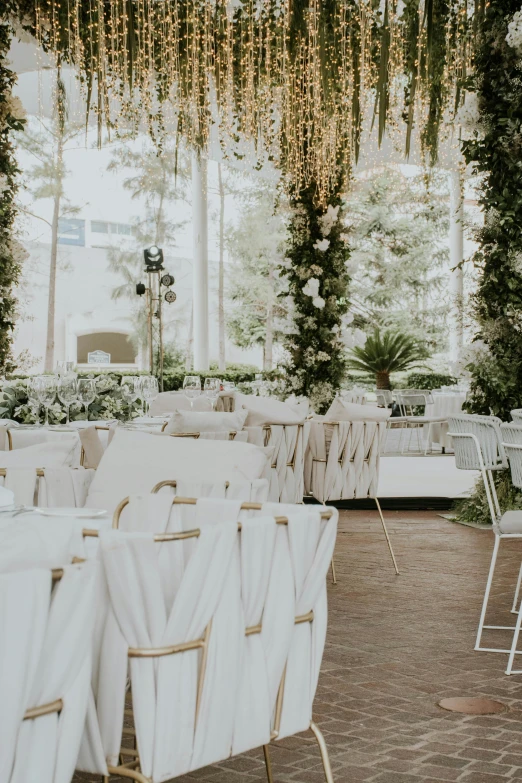 several tables with white linens on them and chairs in the background