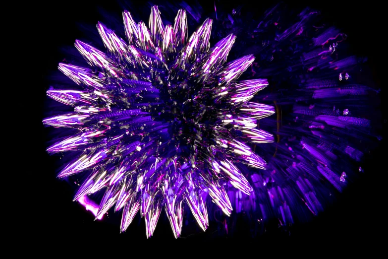 a large colorful purple flower shaped object sitting in the dark