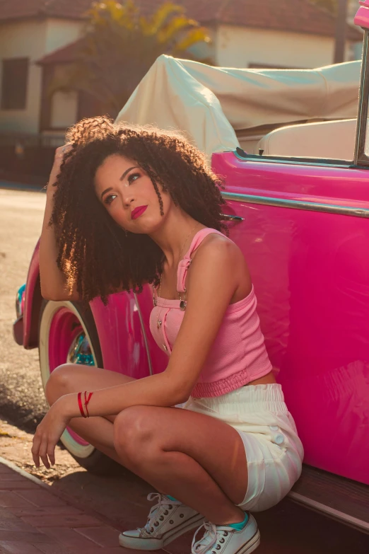 woman sitting on the front of a pink car