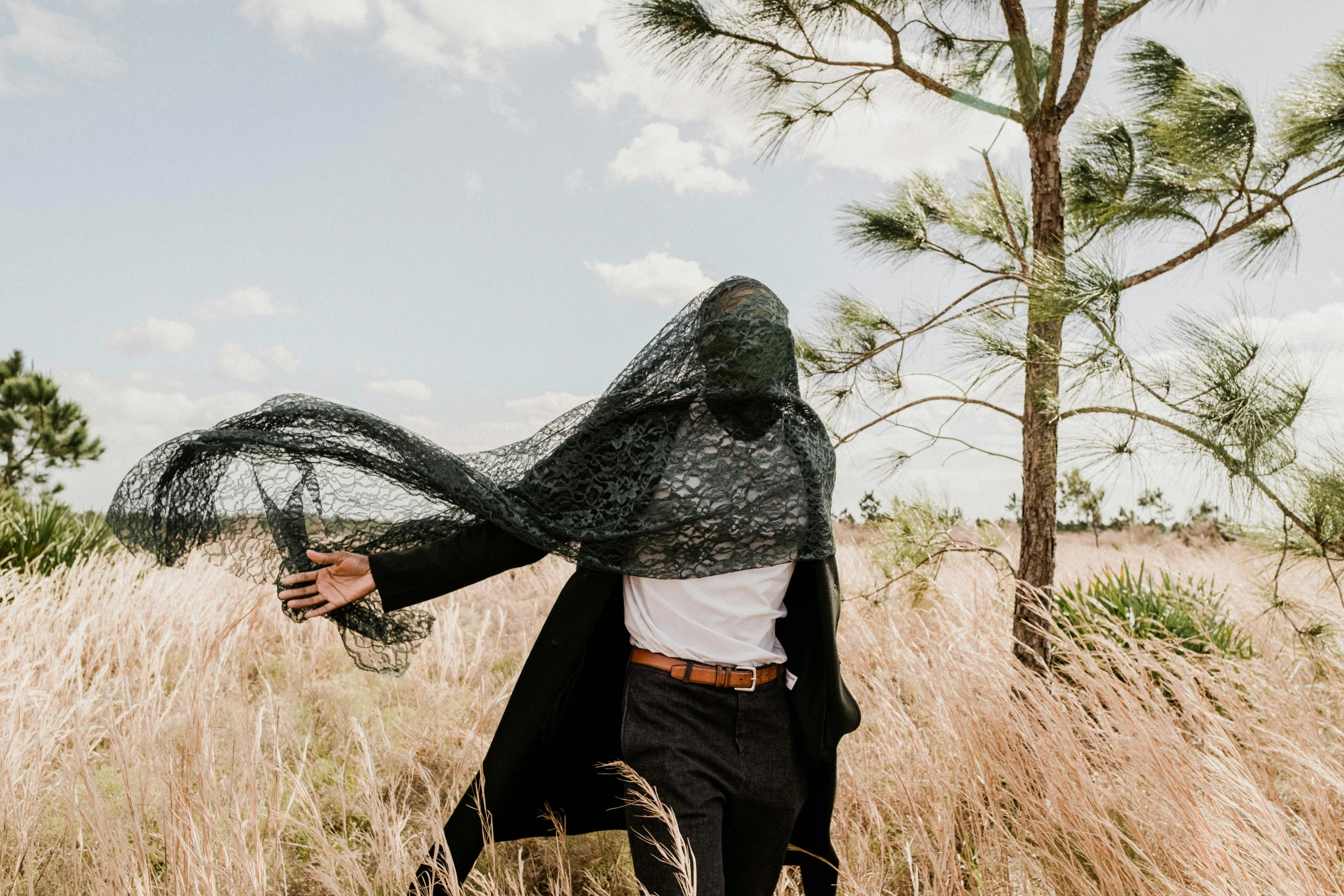 the person is dressed in a black cape and holding a glass