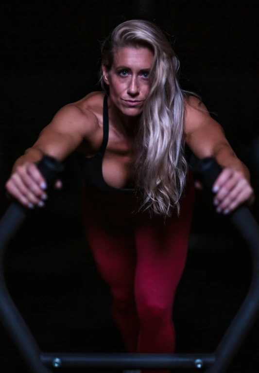 a woman with long hair and very high  stands on a stationary bike