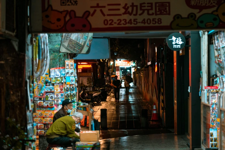 a man sits on the sidewalk by his shop in the rain