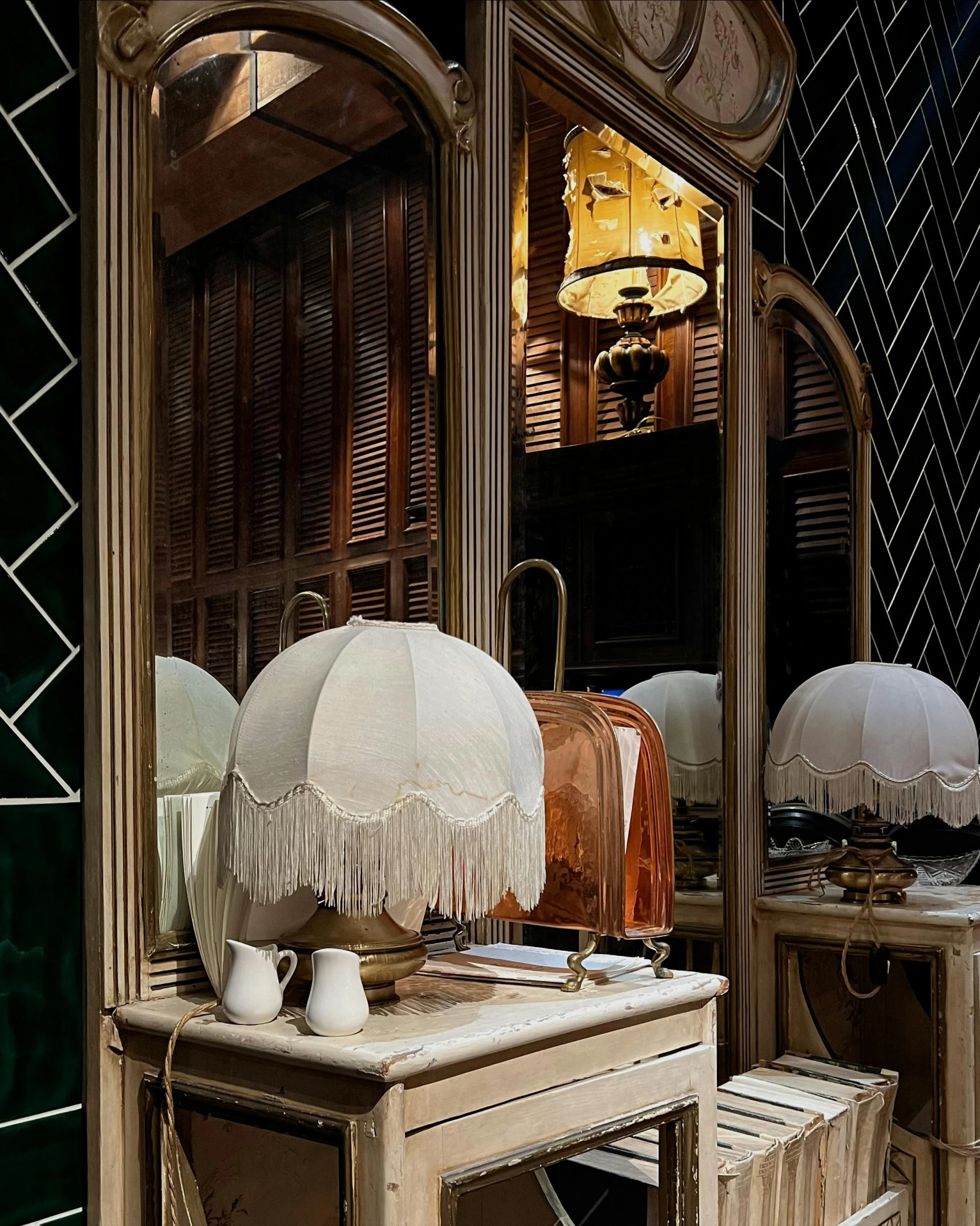 the large mirror reflects a dressing area with a dressing table, stools, and lamps