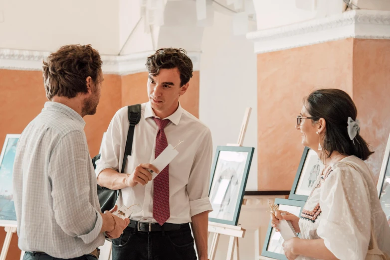 three people standing around while each of them is holding a piece of paper