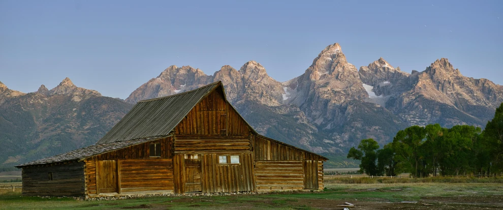 a picture of a barn with the mountains in the background