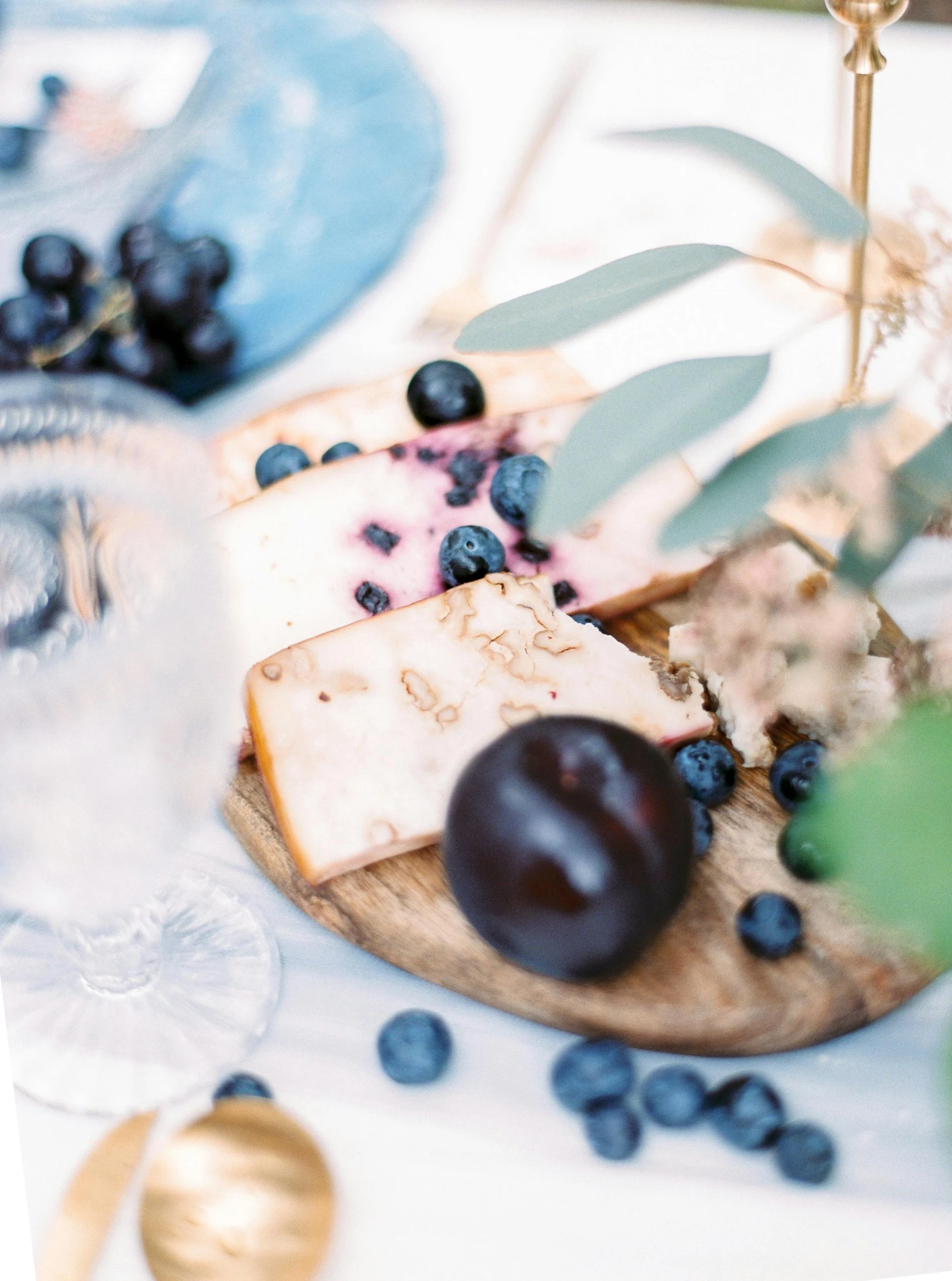 an assortment of cheese and blueberries on a table