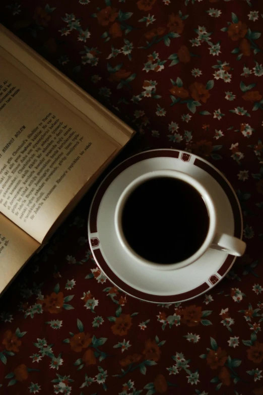 an empty coffee cup next to an open book