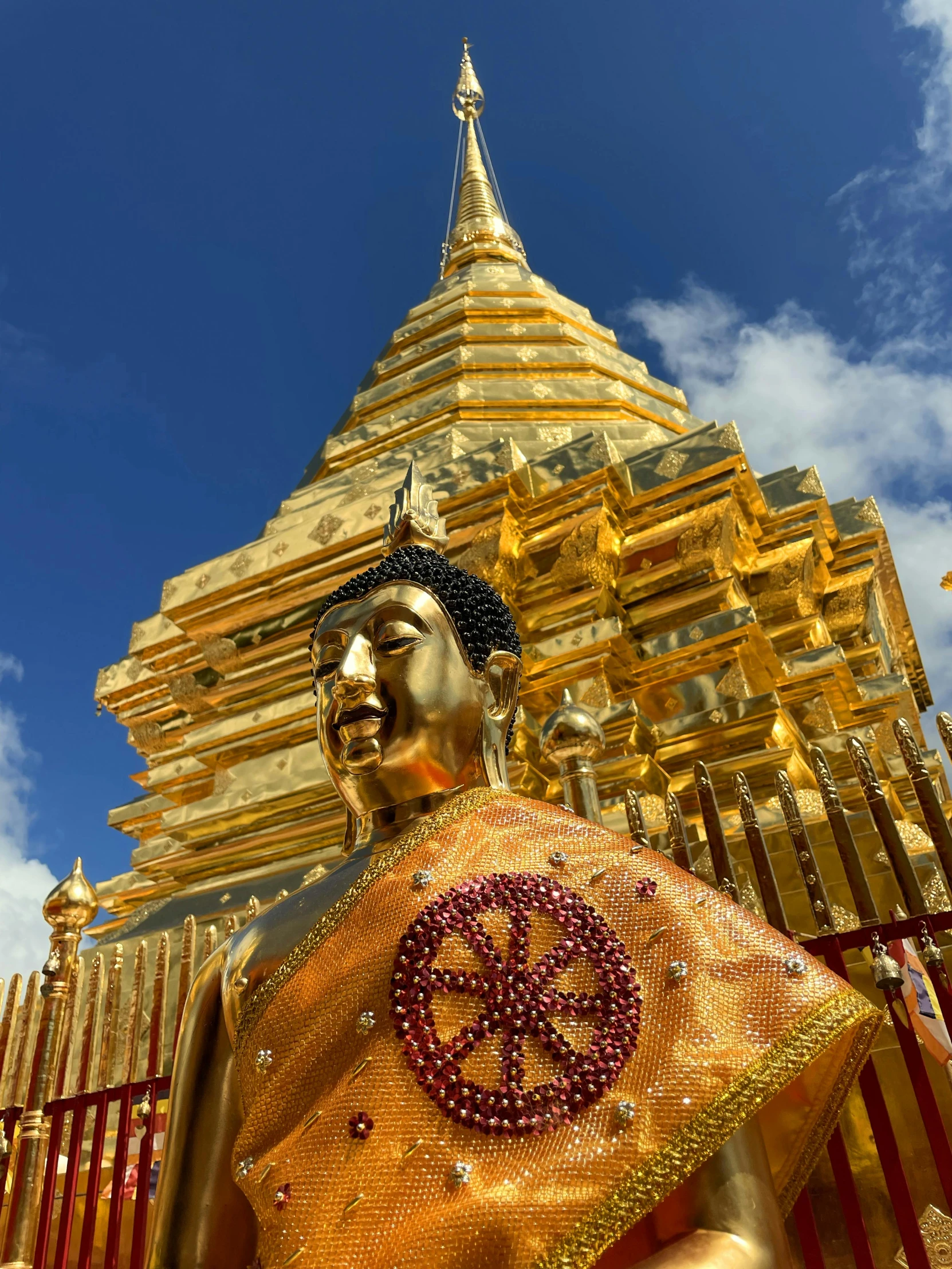 a statue of a gold buddhist monk in front of a golden building