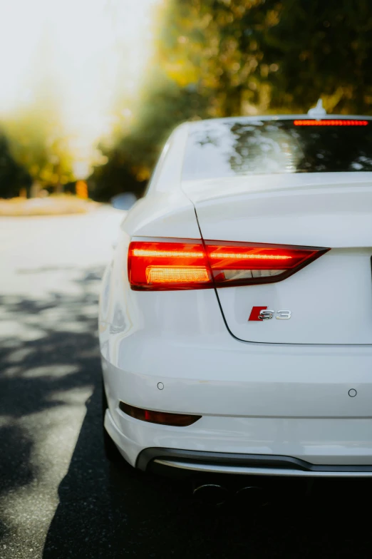 the tail lights of the white sedan parked on a street