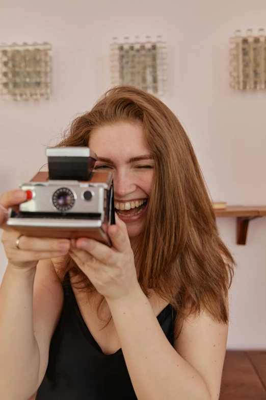 a girl smiling as she looks at an old camera