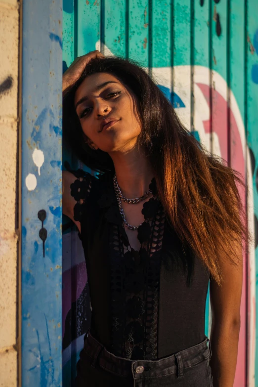 a woman is standing outside, leaning against a wall