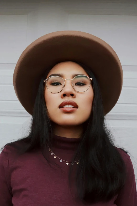 a young woman with glasses and a hat