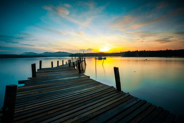 a long dock is by the water during sunset