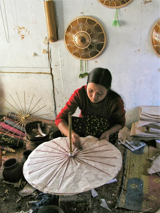 an asian woman making a large umbrella out of fabric