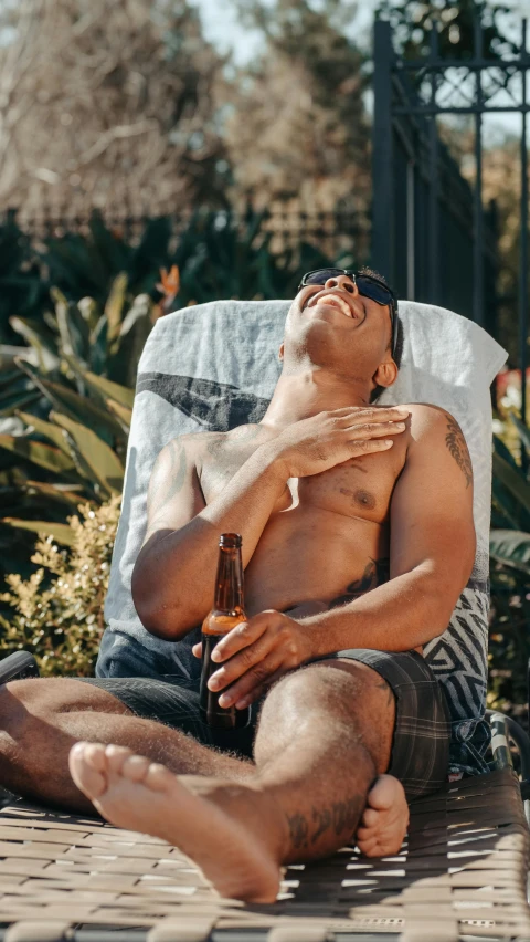 a man on a chair having his shirt off while drinking beer