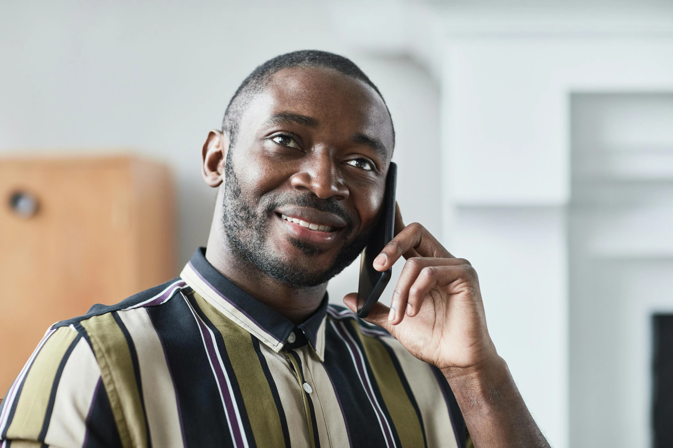 man in striped shirt talking on his phone