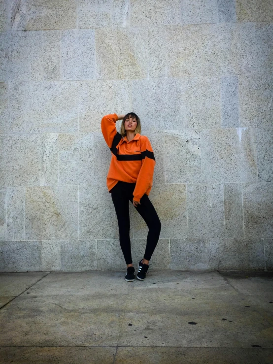 a young woman standing in front of a gray wall