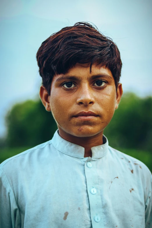 a small boy with no teeth in a green dress shirt