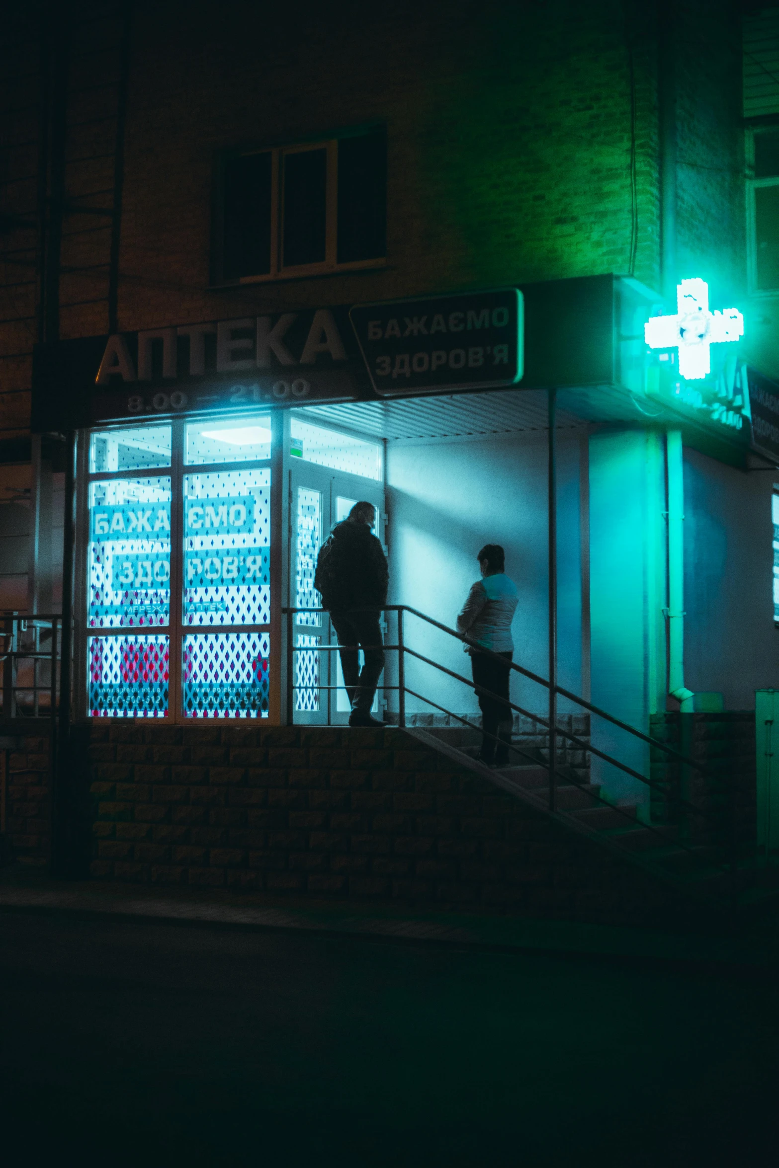 a building with a lit up sign and some people walking up steps