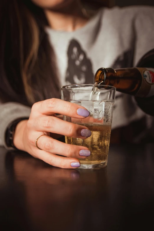 the woman is enjoying her drink and she is pouring the beverage into a glass