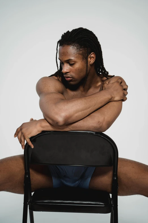 a shirtless man sitting on top of a chair